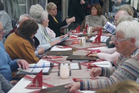 Die Wandertruppe sitzt in einem Restaurant an einem langen Tisch und unterhält sich.