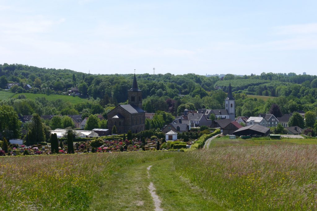 Ausblick von einem Wanderweg in Wülfrath auf einige Häuser und Kirchen.