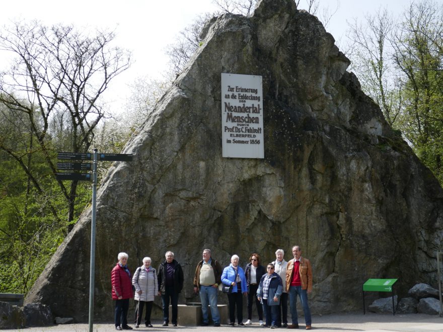 Teilnehmer der Tour posieren vor einem Denkmal zur Entdeckung des Neanderthalers.