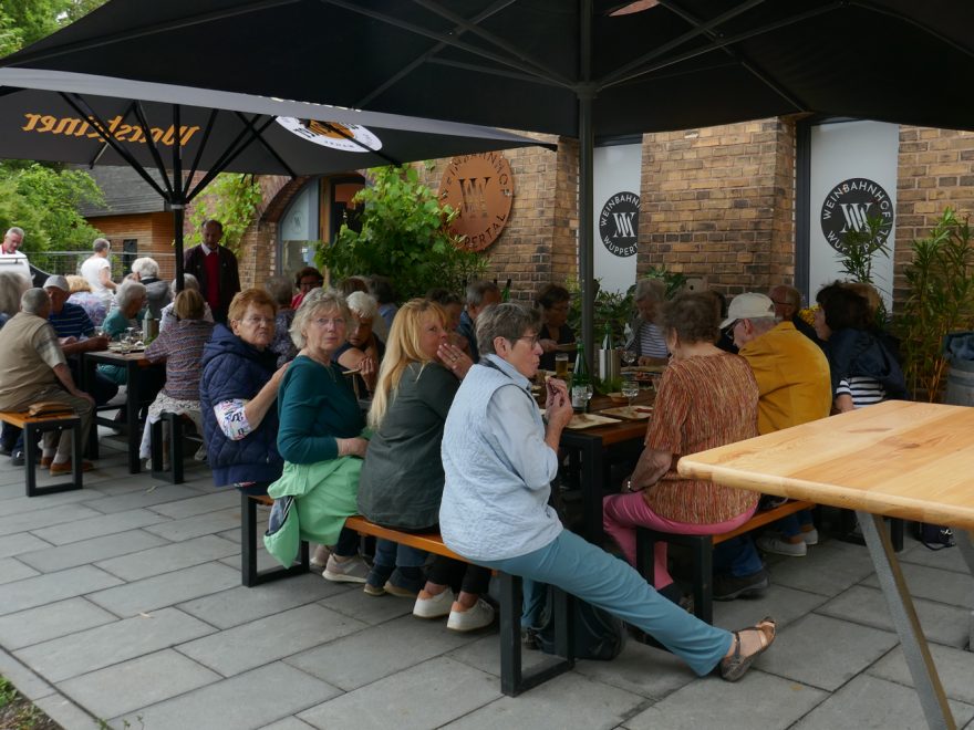 Teilnehmer*innen des Grillnachmittags sitzen an Tischen und essen.